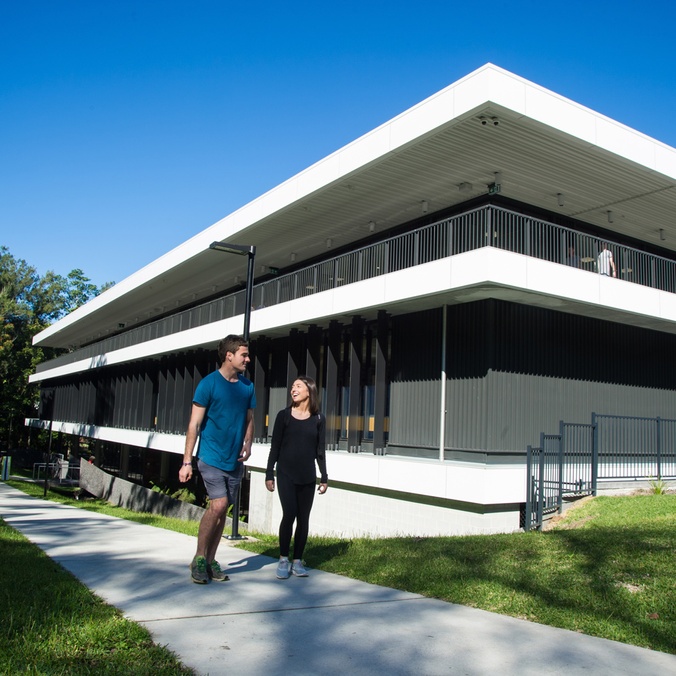 Two students walking past the Learning Centre at the Lismore campus