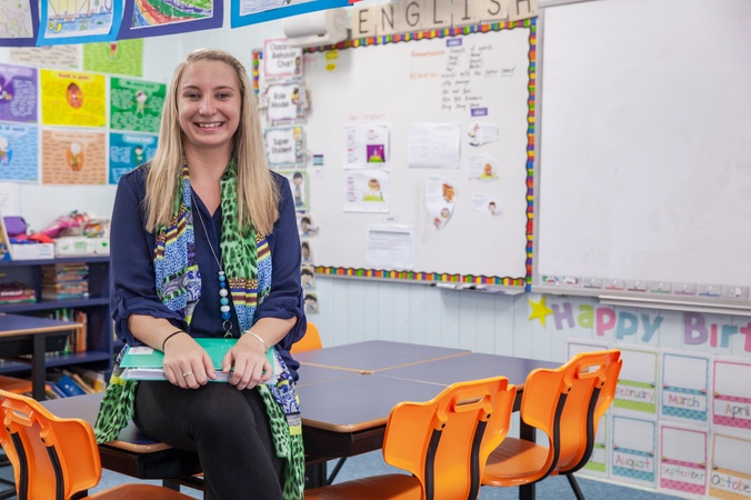 Teacher sitting on a classroom table.
