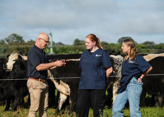 Academic with two students in cow paddock