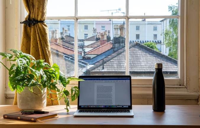 Laptop on desk next to window with views of neighbourhood