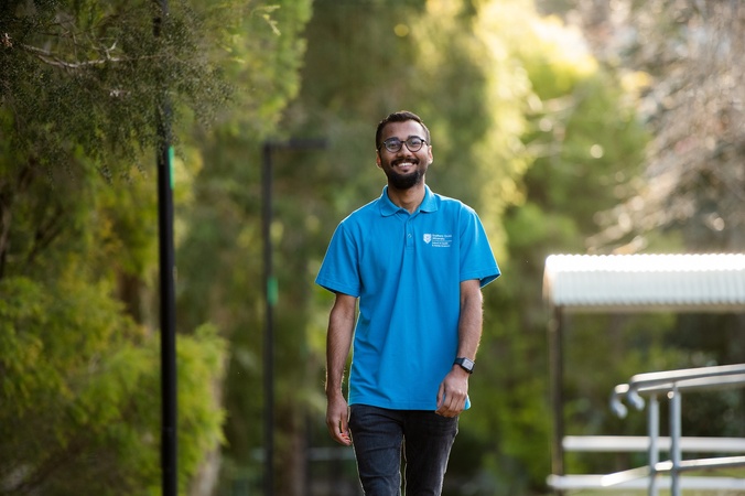 A student in a blue shirt walking on Lismore campus