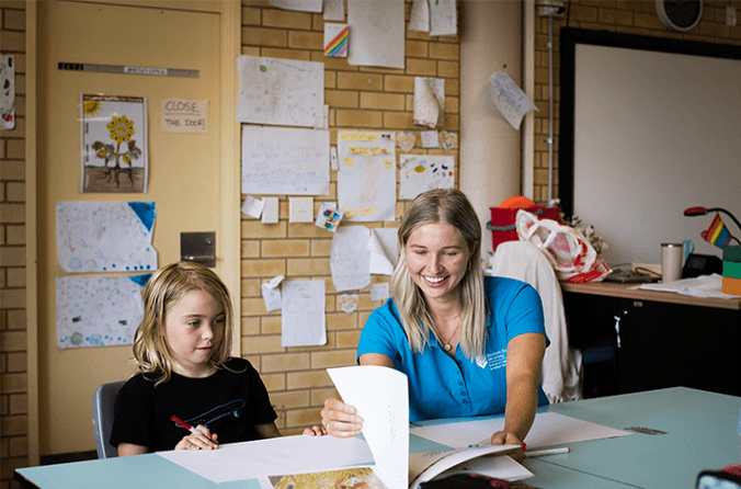 Student from The Living School with occupational therapy student in classroom looking at book