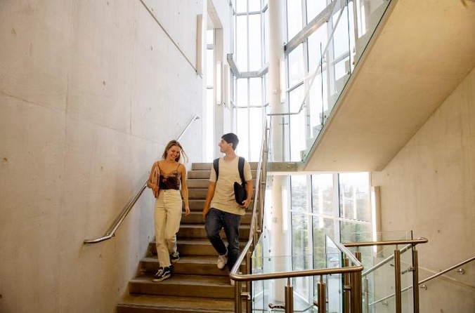 two students descending a staircase smiling