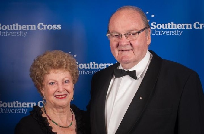 A woman and a man standing against a blue background