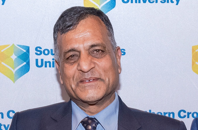 Man in suit in front of SCU media wall