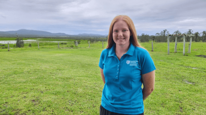Student in blue polo standing in field