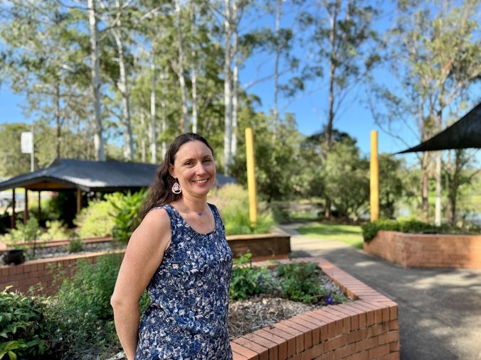 A woman standing in a garden of herbs, trees in the background