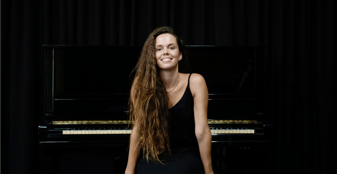 Kaliya smiling while sitting at piano