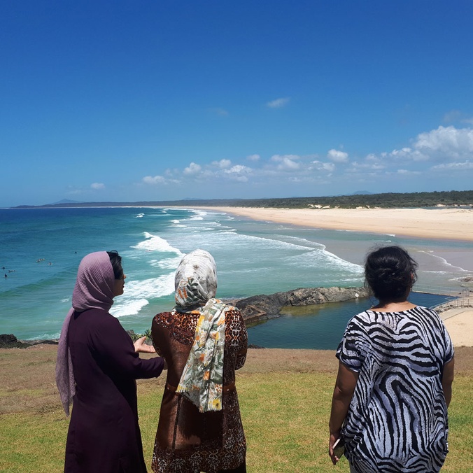Three women standing together looking out to the horizon and ocean