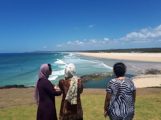 Three women standing together looking out to the horizon and ocean