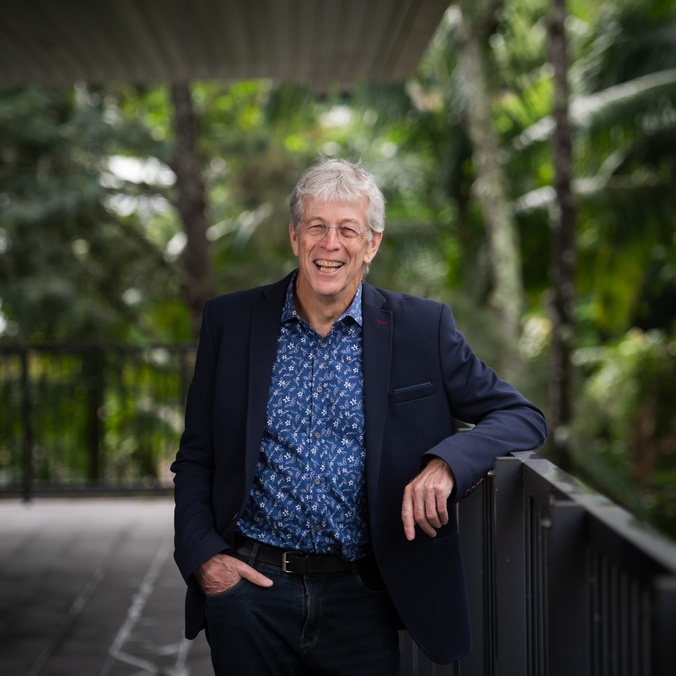 a person standing, leaning on handrail, smiling