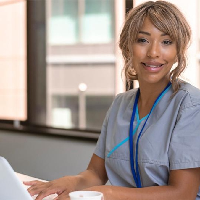 female student sitting at computer and smiling to camera