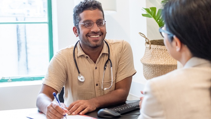 Male doctor with glasses smiling looking at patient