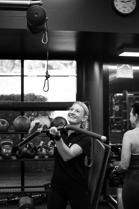 A staff member fixing a lifting gym equipment machine