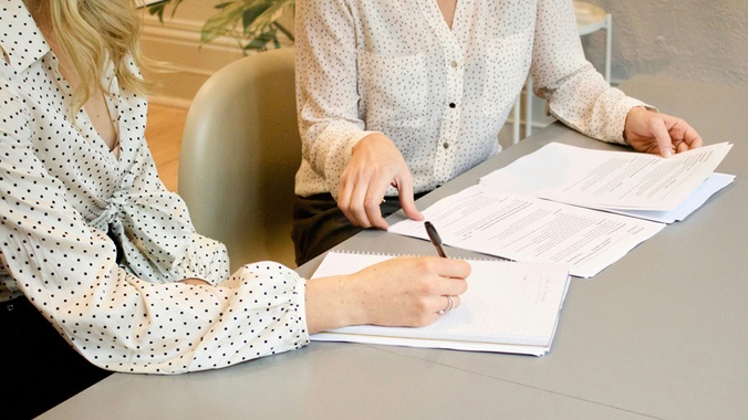 two people at desk signing agreements - image source: gabrielle-henderson-HJckKnwCXxQ-unsplash