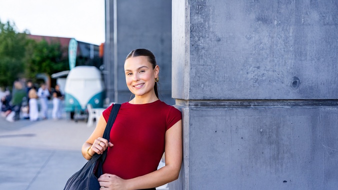 female wearing red top leaning against a wall