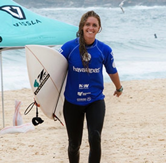 Female surfer coming out of the water with board smiling