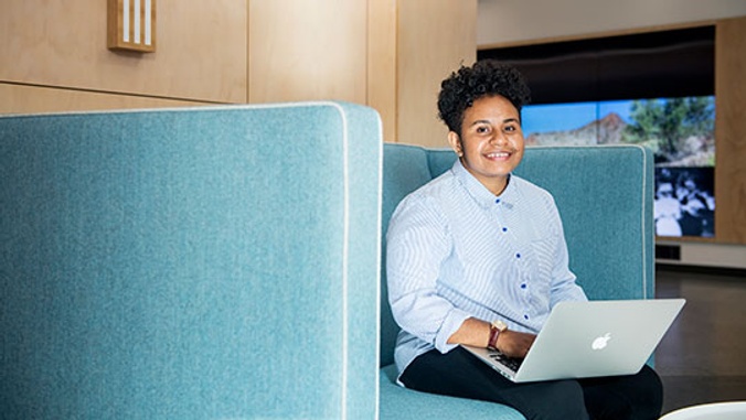 Student sitting on couch with laptop smiling
