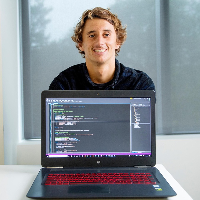 Information Technology Student showing his coding on laptop