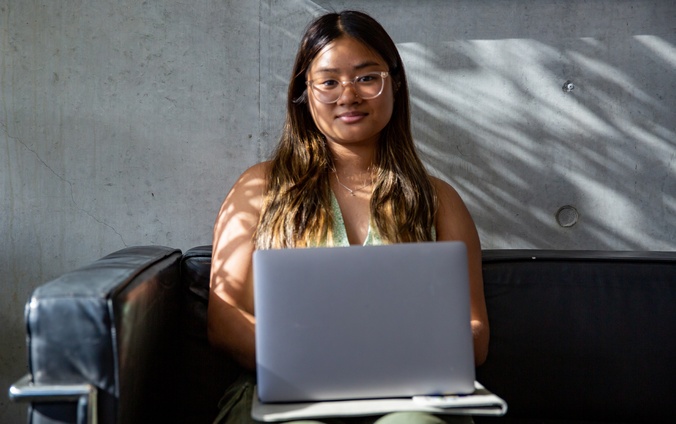 A female student wearing glasses using a laptop.