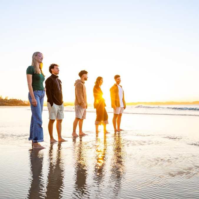 Study abroad students standing on the beach at sunrise