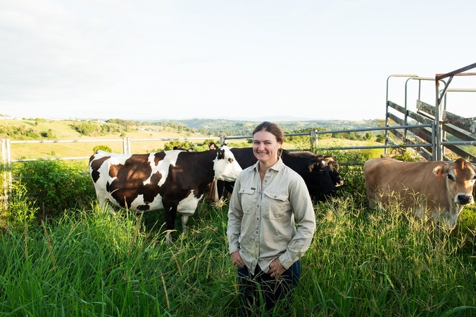 Jackie Morrison stands in front of a herd of cows in a paddock