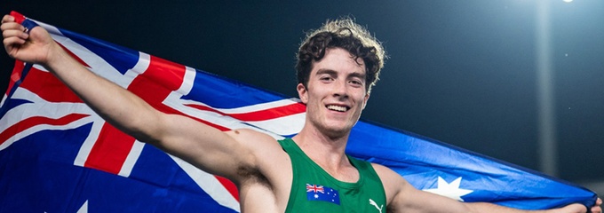 Male runner holding an Australian flag in green running singlet