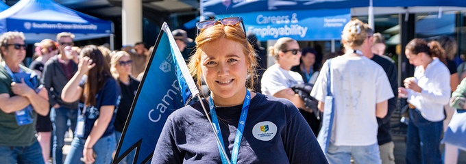 Gabi Quigley holding a campus tour flag at Lismore Open Day