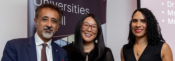 Three people smiling holding award