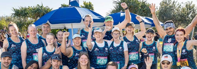 Group or runners in blue singlet shirts smiling at camera