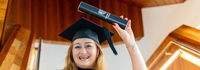 Woman holding certificate in graduation robe