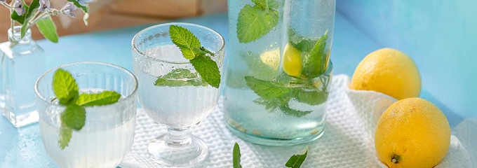 Mint in water with lemons on a table with flowers