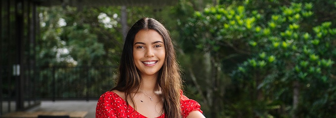 femail student standing on a balcony with green garden in background