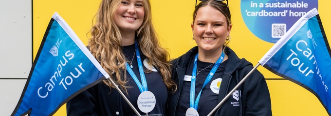 Two female students holding campus rous flags