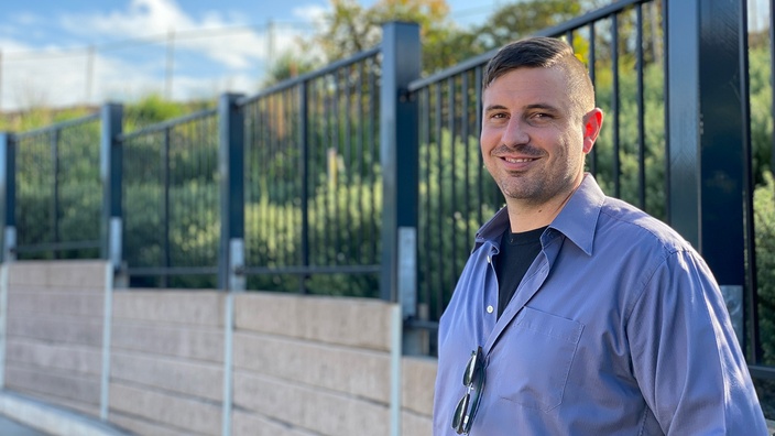 A picture of Engineering graduate Jake Bentley , outside, he is leaning against a fence and smiling at the camera