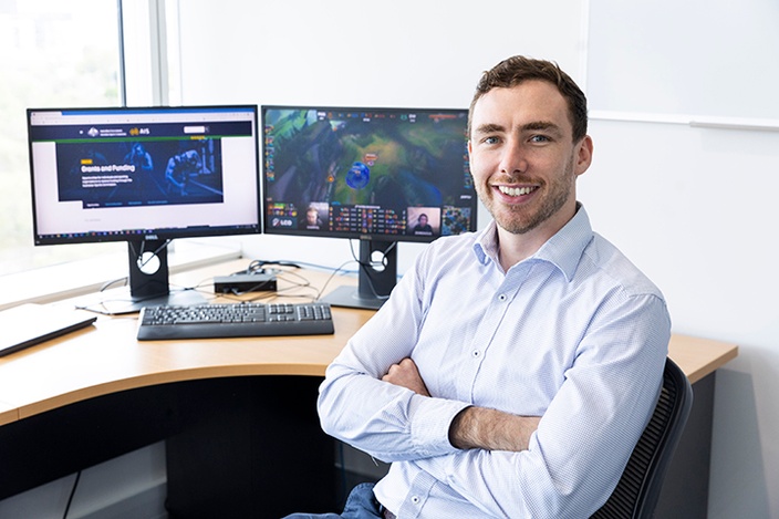 A man in front of screens showing League of Legends esports