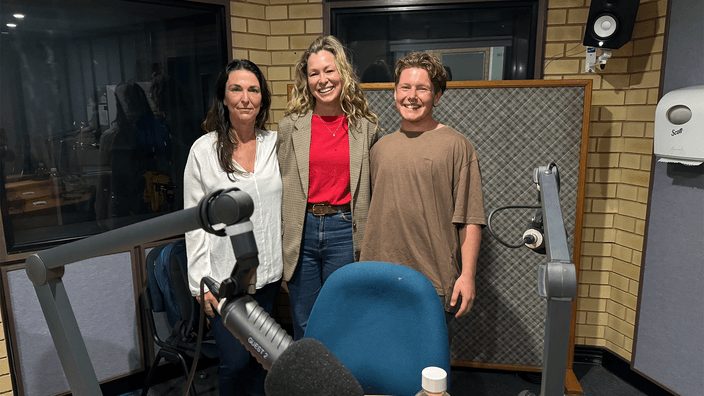 Kylie, Aimee and River in podcast studio with microphone in foreground