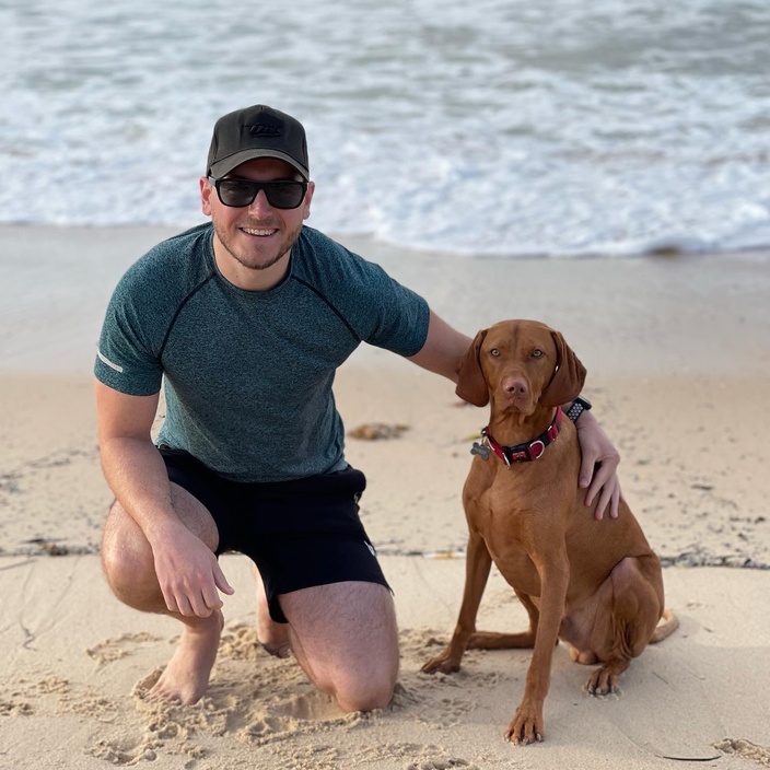 MBA graduate Andrew Nichols with his dog, Huxley at the beach