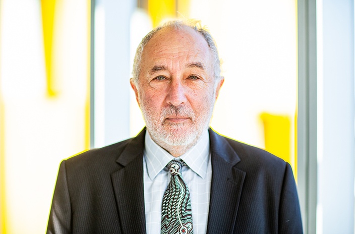 A man in a suit and tie against a yellow wall