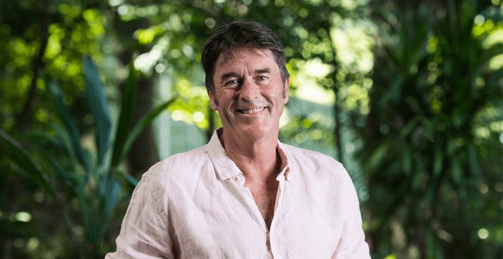 Man in linen shirt smiling with trees in background