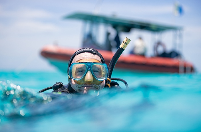 A scuba diver at the surface of the water, with a boat in the background