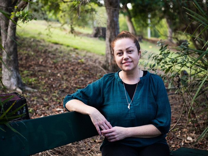 A woman sitting on a bench in a parkland setting