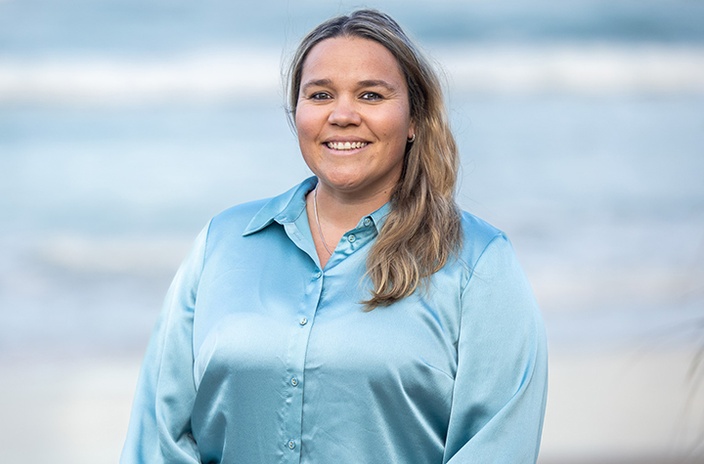 A woman in a pale blue long sleeve shirt at the beach