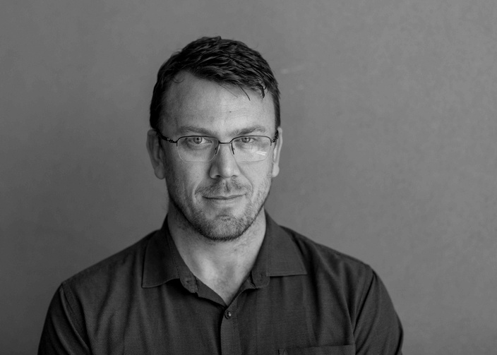 A black and white image of a man in an open collar shirt wearing glasses