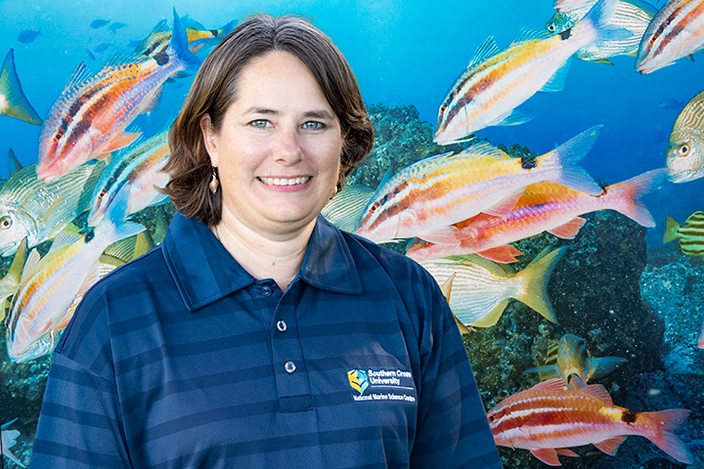 A woman wearing a SCU logo shirt in front of a fish mural