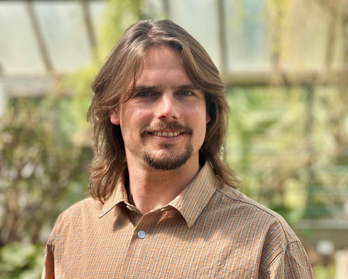 A man with longish hair and a goatee smiling