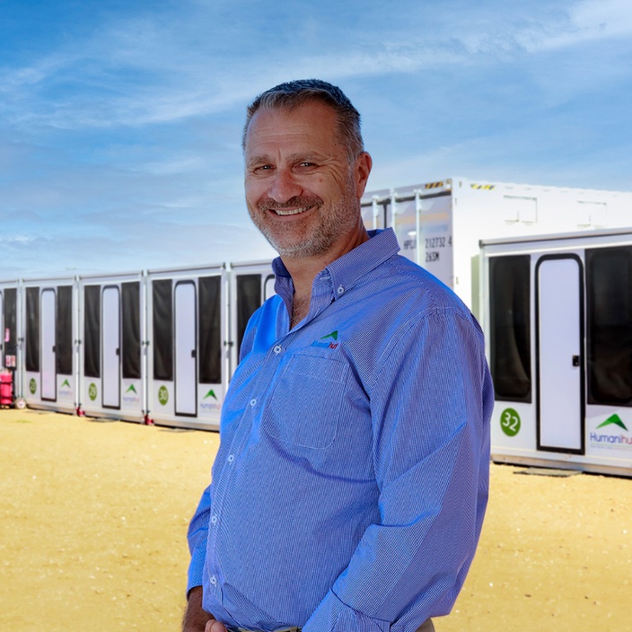 Man smiling at camera in front of emergency shelters
