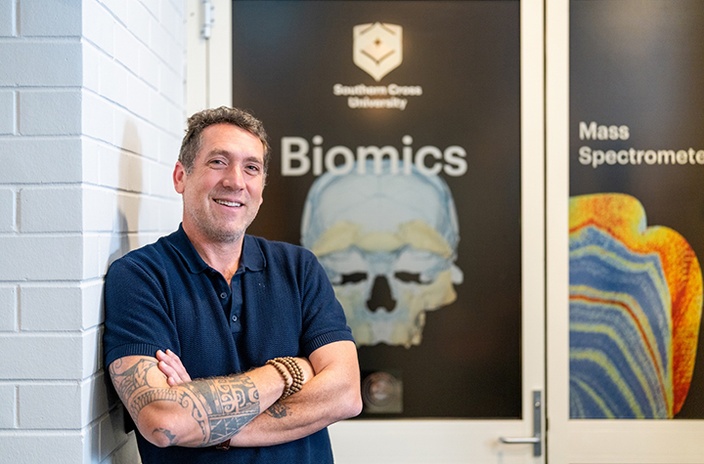 A man with tattoos standing in front of laboratory with an image of a skull on the door
