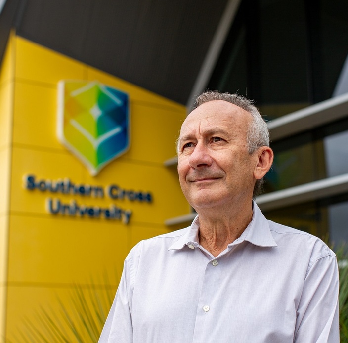 A man looking off camera, a campus building in the background