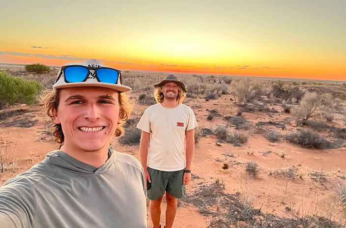Two men in the desert at sunset
